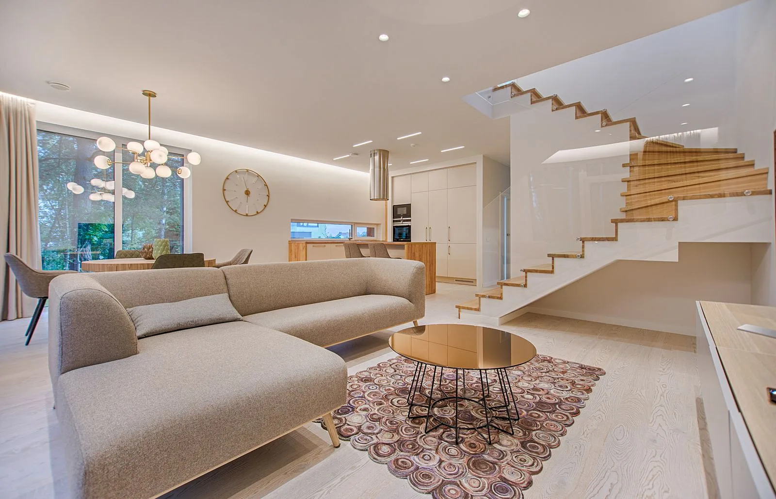 Open-plan living area with layered neutral furnishings and architectural staircase